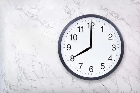 Wall clock show eight o'clock on white marble texture. Office clock show 8pm or Stock Photos