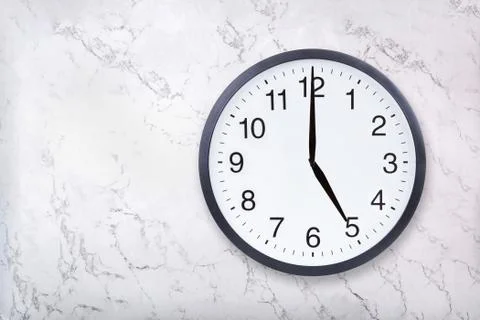 Wall clock show five o'clock on white marble texture. Office clock show 5pm or Stock Photos