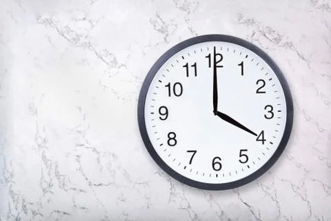 Wall clock show four o'clock on white marble texture. Office clock show 4pm or Stock Photos