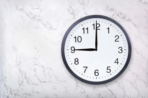 Wall clock show nine o'clock on white marble texture. Office clock show 9pm or Stock Photos