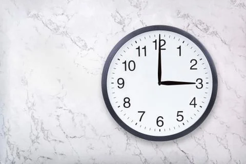 Wall clock show three o'clock on white marble texture. Office clock show 3pm or Stock Photos