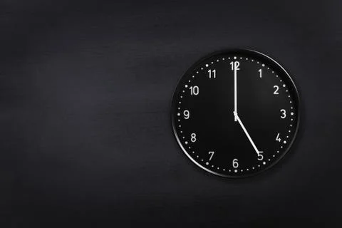 Wall clock showing five o'clock on black chalkboard background. Office clock Stock Photos