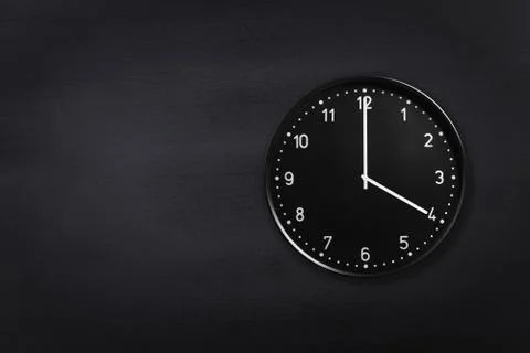 Wall clock showing four o'clock on black chalkboard background. Office clock Stock Photos