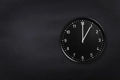 Wall clock showing one o'clock on black chalkboard background. Office clock Stock Photos