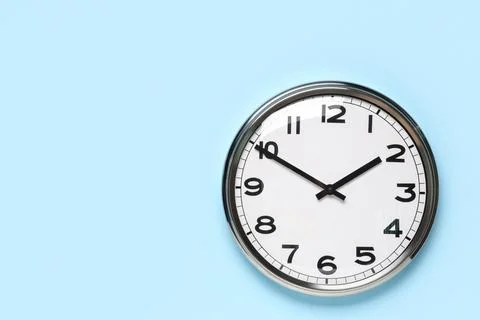 Wall clock showing time on blue background Stock Photos