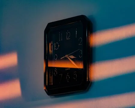 Wall clock with sunlight and shadow stripes Stock Photos