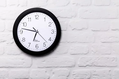Wall clock on white brick wall Stock Photos