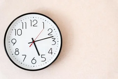 Wall clock with a white dial, black edging and black arrows free space for te Stock Photos