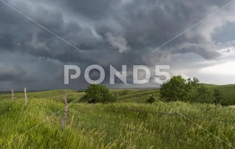 Wall clouds spin below a tornado super-cell hovering and kicking up dust into Stock-Fotos