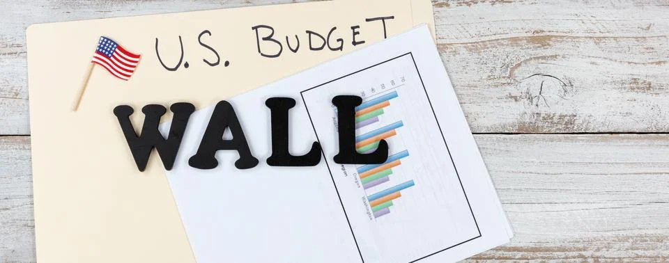 Wall construction topic with U.S. Budget concerns on rustic wooden desktop fo Stock Photos