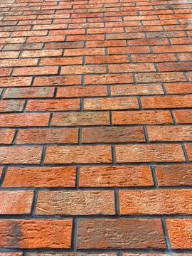 A wall covered in bricks shows various shades of orange and brown. The bricks 写真素材