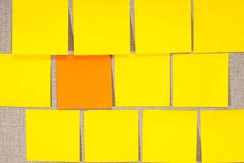 A wall covered in yellow sticky notes with one orange Stock Photos