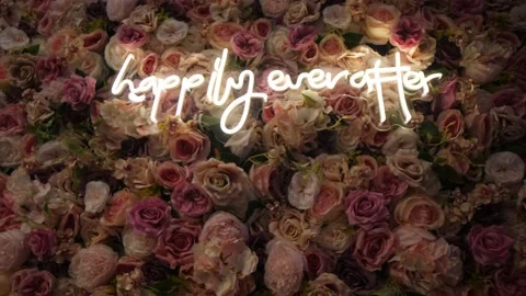 Wall decorated with delicate roses with a "happily ever after" white neon sign o Stock Footage 230911994