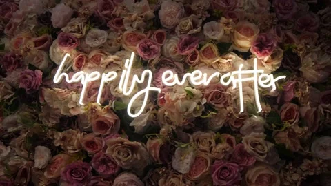 Wall decorated with delicate roses with a "happily ever after" white neon sign o Stock Footage 230911999