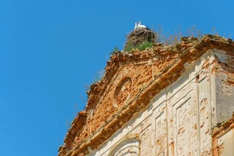 The wall of a dilapidated old red brick house against a blue sky background.  Stock Photos