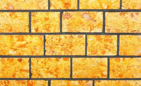 The wall is faced with bright yellow irregular rectangular stone tiles. 스톡 사진