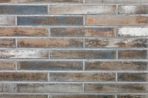 The wall is faced with old oblong rough tiles in horizontal design. Wall text Stock Photos