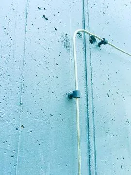 A wall features a metal pipe secured by a bracket. The wall has rough texture 库存照片