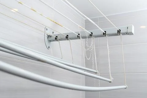 Wall fixed laundry drying rack in tiled bathroom with frayed cords and rust Stock Photos