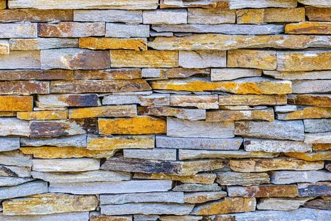 A wall of flat horizontally arranged multicolored stones. Stock Photos