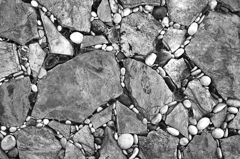 A wall, a floor with cracks, consisting of many big and small stones of black Stock-Fotos