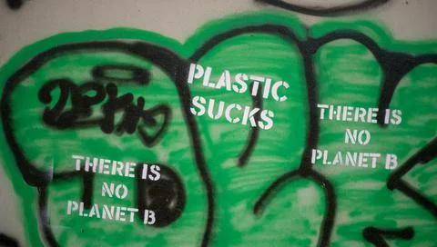 Wall graffiti featuring "plastic sucks" and "There is no planet B" slogan Stock Photos
