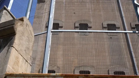 A wall of a gray prison building through a barbed wire fence. bottom view. Video stock 125643306