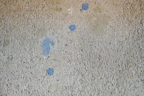 Wall of gray solid, shaggy, embossed building concrete with spots of blue pai Fotos de archivo