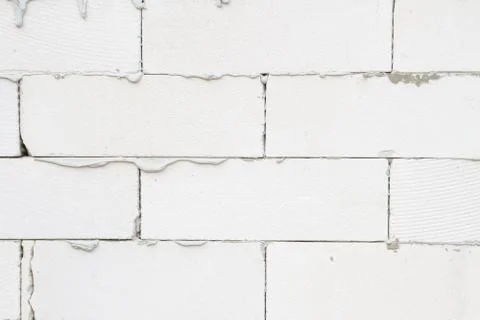The wall of the house is made of light gray brick with stains of cement Stock Photos