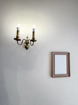 Wall lamp and empty picture frame on white wall in a room Stock Photos