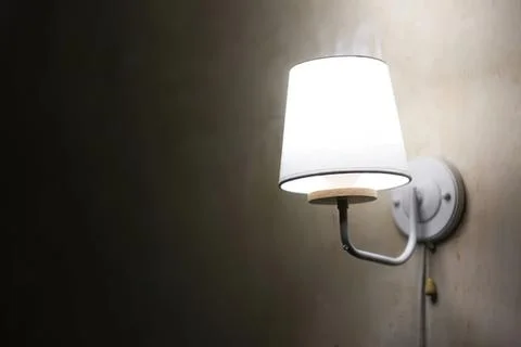 Wall lamp with white shade lighting a room Stock Photos