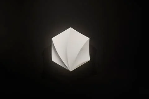 Wall lamp, white with soft light on a black background, interesting shape and Stock Photos