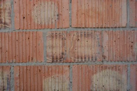 Wall of large red corrugated bricks with gray cement masonry. Stock Photos