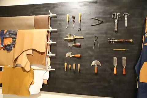 A wall of leather crafting tools, including work aprons and scissors, displ.. Stock Photos