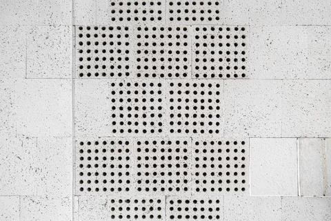 The wall is lined with decorative white limestone tiles with holes Stock Photos