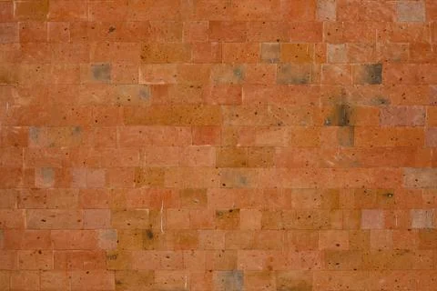 The wall is lined with red volcanic tuff tiles. Textured wall mockup. Stock Photos