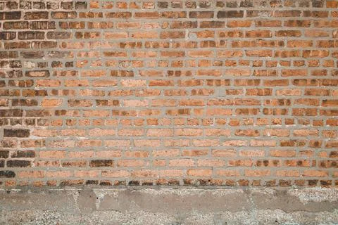 A wall made of bricks stands with various shades of brown. The bricks show th 库存照片