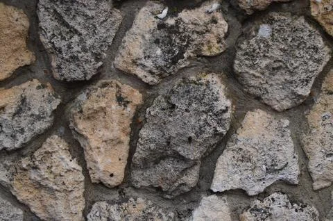 A wall made of large rocks with a rough texture. Stock Photos
