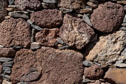 A wall made of large rocks with a rough texture Stock Photos