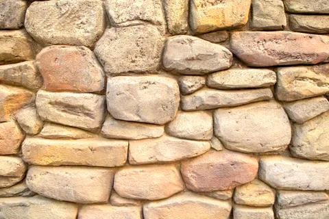 Wall made of light massive natural stones. Beige background for wallpapers. Stock Photos