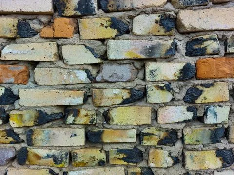 Wall made of old baked bricks, red brown white yellow black gray, close-up Stock Photos