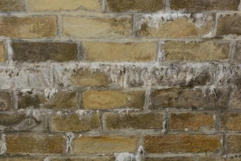 The wall is made of old brown bricks with stalactites. Stock Photos