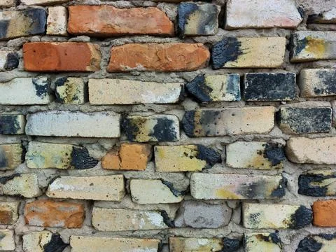 Wall made of old multi-colored bricks red black white yellow Stock Photos