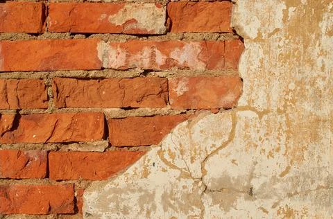 The wall is made of red brick with fallen plaster. Background. Stock Photos