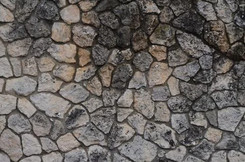 A wall made of stone with a rough texture. Stock Photos
