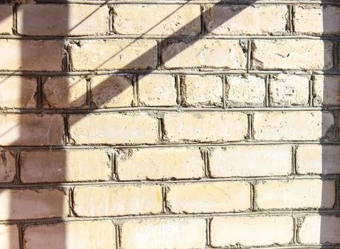 The wall is made of white brick with sharp shadows from the sun. 스톡 사진
