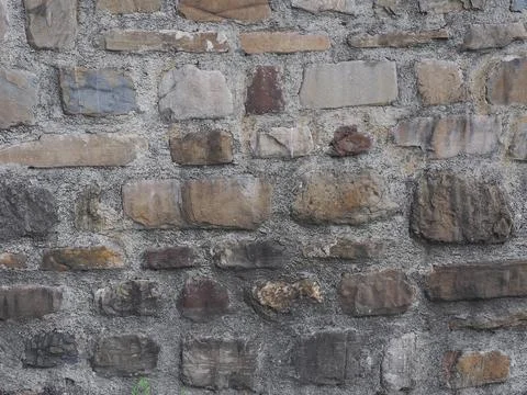 Wall with masonry of rough stone of various shapes and a thick gray layer of Stock Photos