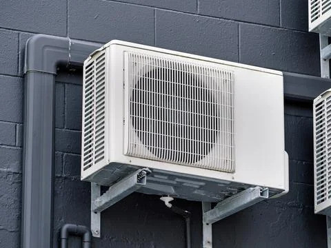 Wall-Mounted Air Conditioning Unit with Piping on Dark Brick Wall Stock Photos