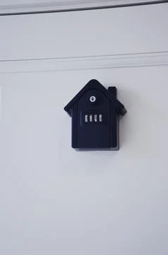A wall mounted black key lock box with a combination lock mounted above a t.. Фото