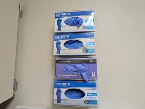 Wall-mounted boxes of blue disposable medical gloves inside a doctor’s office Stock Photos